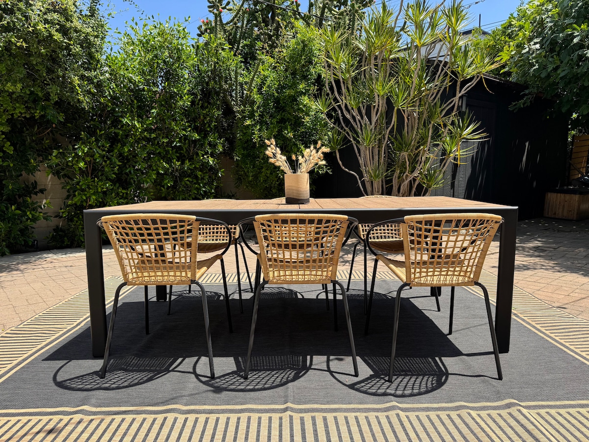 Outdoor dining table with wicker chairs under the string lights