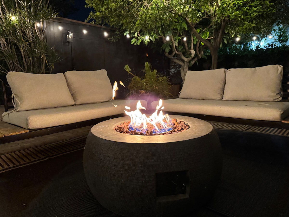 The gas fire pit lit at night beside the outdoor sofa