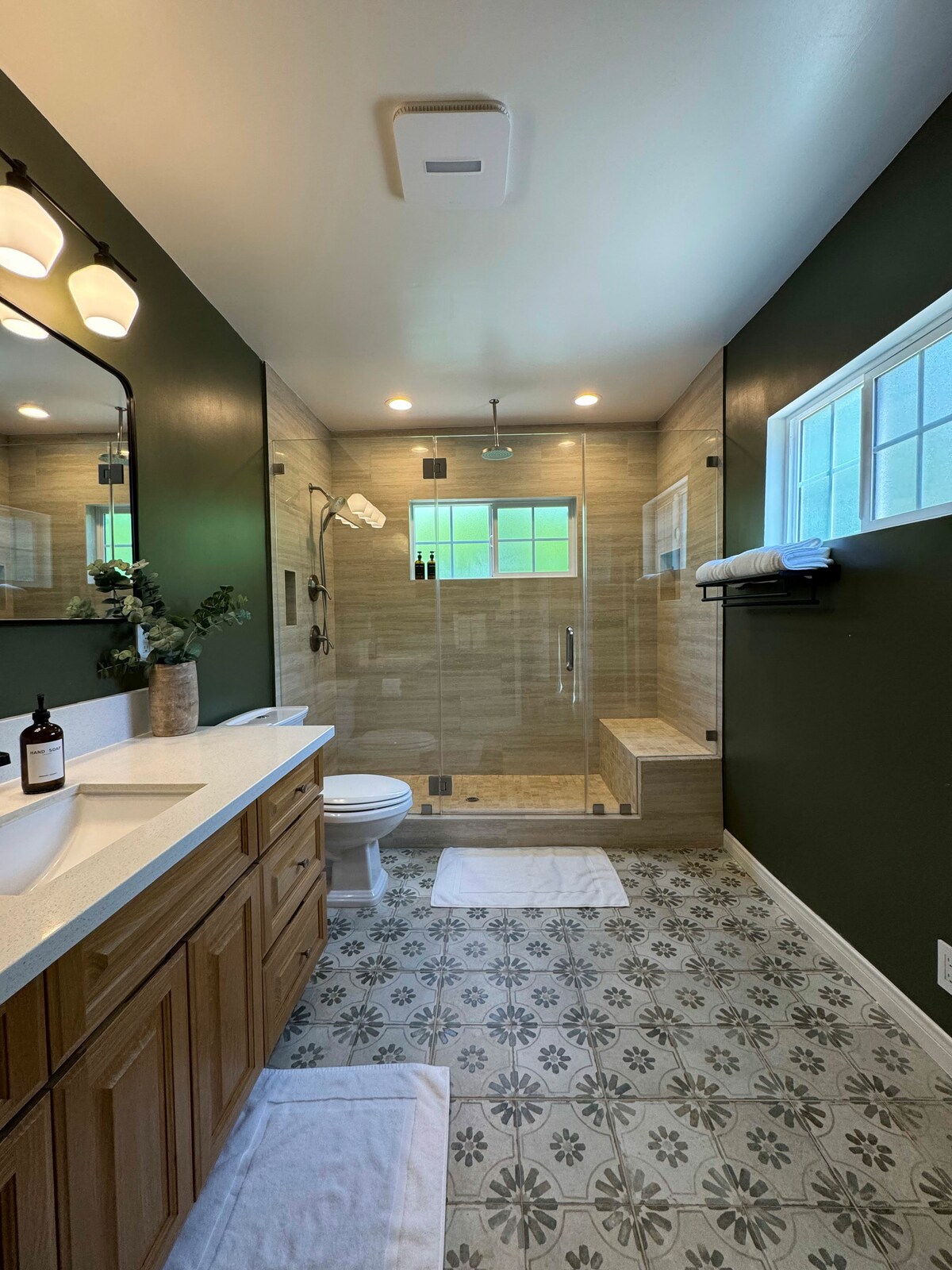 Walk in rainfall shower behind glass with a deep green wall