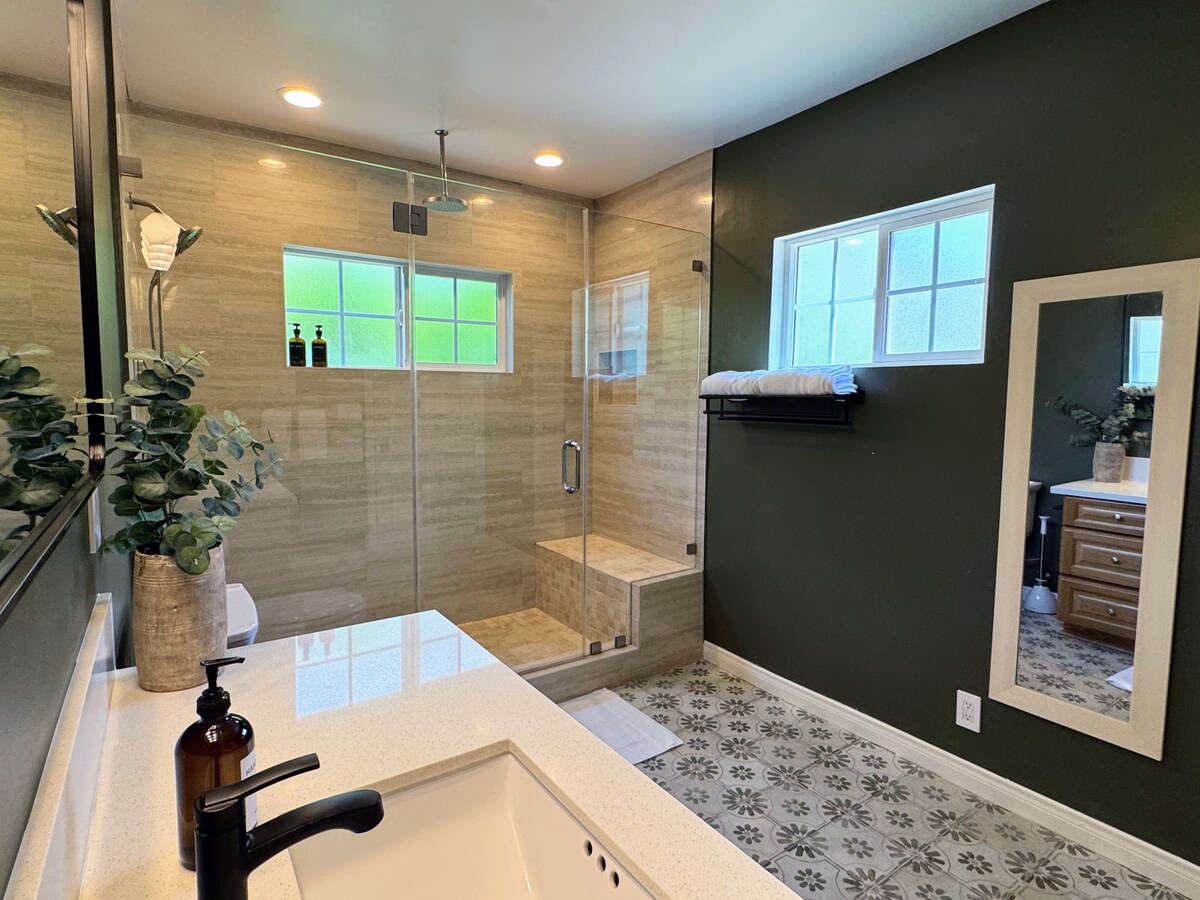 Renovated bathroom with patterned tile floor, glass shower, and vanity