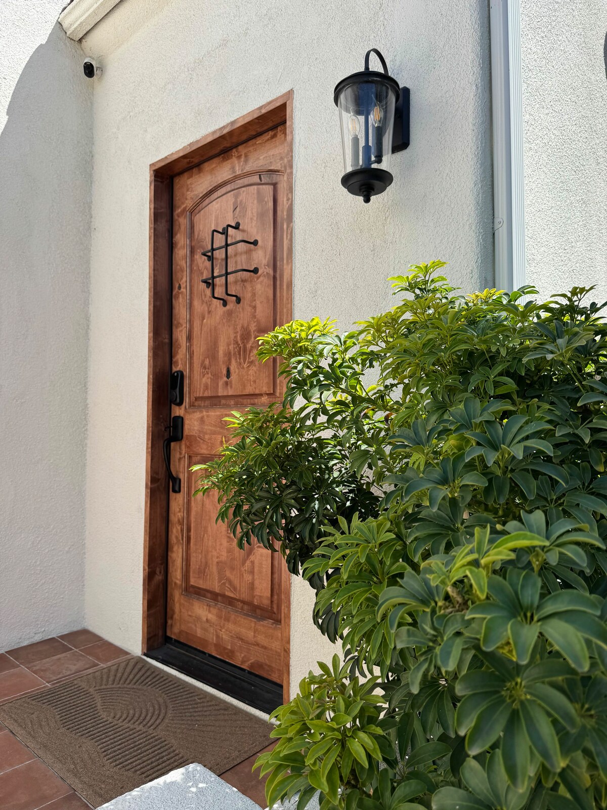 The arched wood front door with iron detail and a lantern