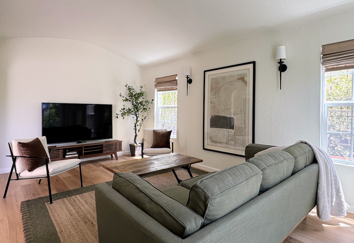Living room with a deep green sofa, art, and afternoon light